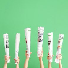 Female hands with newspapers on color background