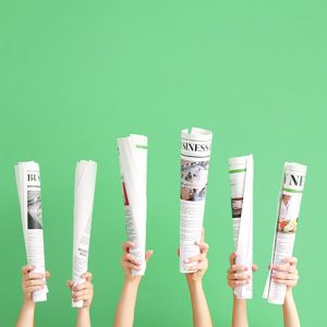 Female hands with newspapers on color background